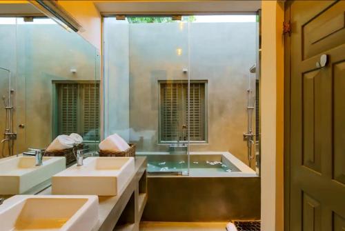 斯里贾亚瓦德纳普拉科特Angam Suites Colombo的浴室设有2个水槽、浴缸和镜子
