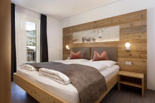 圣坎迪朵Dolomite Apartments Winklwiese 6&7的一间卧室设有一张带木墙的大床
