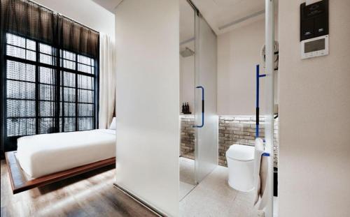 上海上海外滩沙美大楼ZHotel的一间卧室设有一张床和一个带卫生间的玻璃门