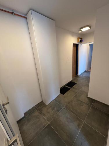 卡托维兹Pokoje Brynów的一条空的走廊,铺着瓷砖地板,墙壁白色
