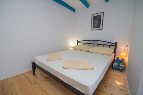 大洛希尼Ferienhaus mit Privatpool für 4 Personen ca 70 qm in Veli Lošinj, Kvarner Bucht Losinj的一间卧室配有一张铺有木地板的白色床单。