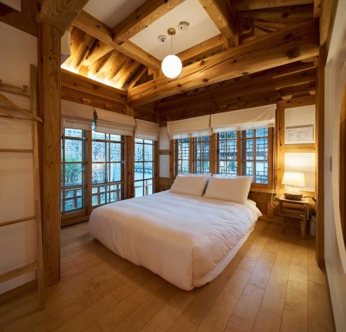 首尔Luxury hanok with private bathtub - SN01的卧室设有白色的床和木制天花板。