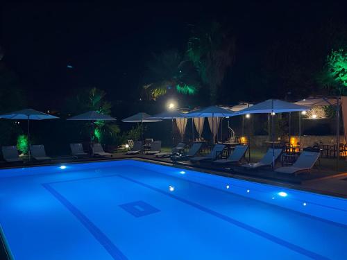 达特恰MAVİ ROTA BUTİK OTEL的夜间游泳池,配有椅子和遮阳伞