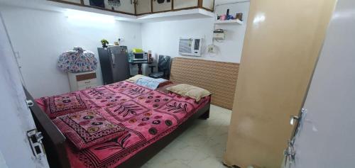 钦奈Halls Tower的小房间,配有一张带粉红色毯子的床