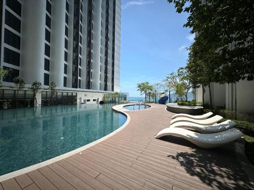 哥打京那巴鲁Summer Seaview Studio Apartment at Kota Kinabalu City Centre的一座带躺椅的游泳池位于大楼旁