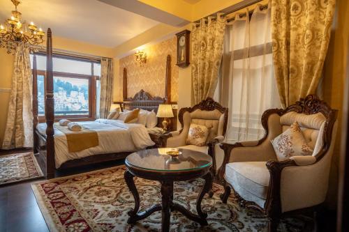 西姆拉Rajkamal-The Himalayan Heritage的卧室配有一张床和一张桌子及椅子