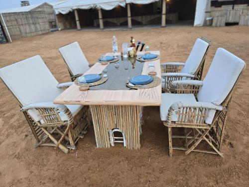 MarghamMargham Desert Safari Camp的沙子中的一张木桌和椅子