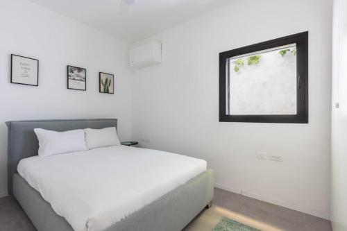 特拉维夫Eclectic Vision by TLV2RENT的白色的卧室设有床和窗户