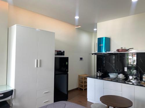 胡志明市LUCY HOTEL & APARTMENT的厨房配有白色橱柜和黑色冰箱。