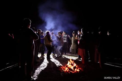 锡卡都Mantri Bai Camping Site Deosai的一群人晚上站在火炉旁