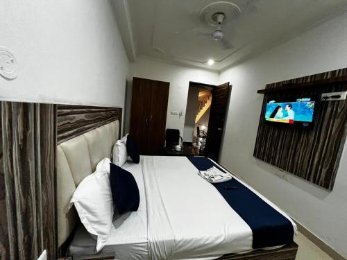 新德里wide Hotel的卧室配有一张床铺,墙上配有电视