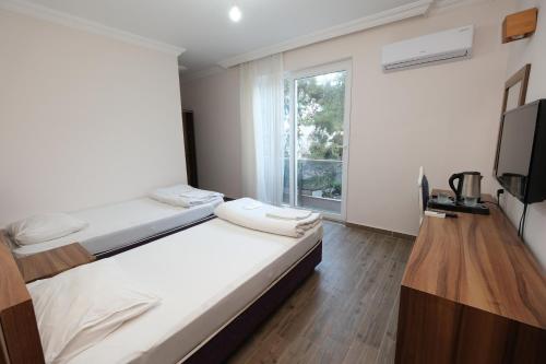 安塔利亚Venüs Hotel的一间卧室设有两张床、一台电视和一扇窗户。