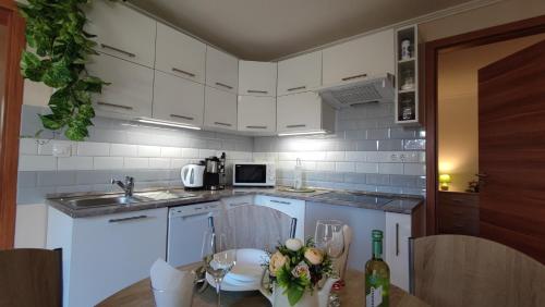 加尔多尼Limonádé Apartman的厨房配有白色橱柜和鲜花桌