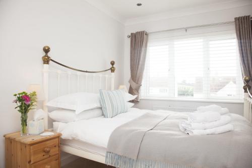 帕兹托Trevose House的一间卧室设有两张带白色床单的床和窗户。