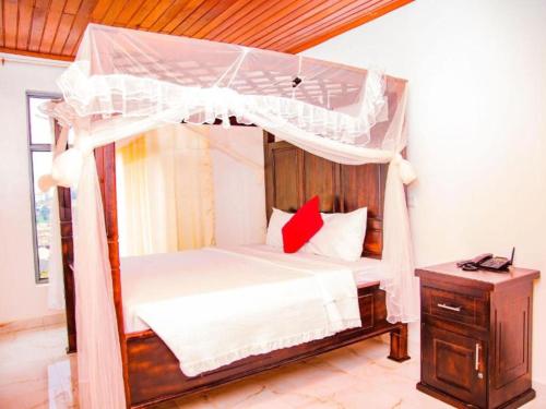 基加利KEZA Home的一间卧室配有天蓬床和床头柜