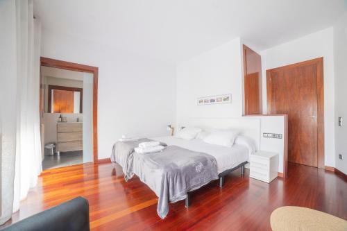 维克Mazi Apartments Colón的卧室设有一张白色大床和木地板