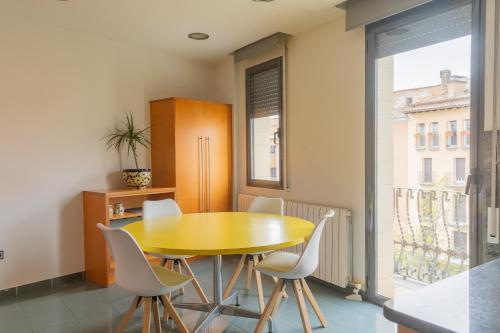 维克Mazi Apartments Colón的一间设有黄色桌子和白色椅子的用餐室