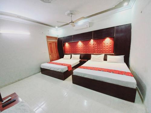 卡拉奇Rose Palace Guest House的一间卧室配有两张床,床头上配有红灯。