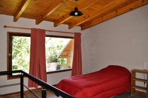 圣卡洛斯-德巴里洛切Cabaña en Villa Los Coihues的一间卧室设有红色的床和窗户。