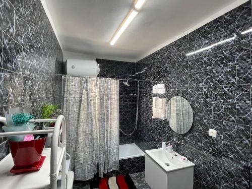 地拉那Villa Oni的黑色瓷砖浴室设有卫生间和水槽