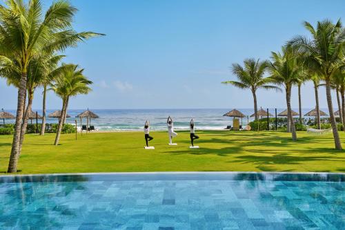 会安Wyndham Hoi An Royal Beachfront Resort & Villas的一群人在海滩边做瑜伽