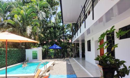 雅科Casajungla Hostel的一个带遮阳伞和房子的室外游泳池