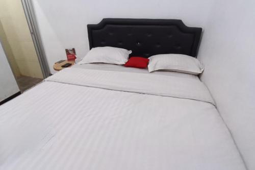 KlatenOYO 93885 D'harjo Guesthouse的一张带黑色床头板的白色床和两个枕头