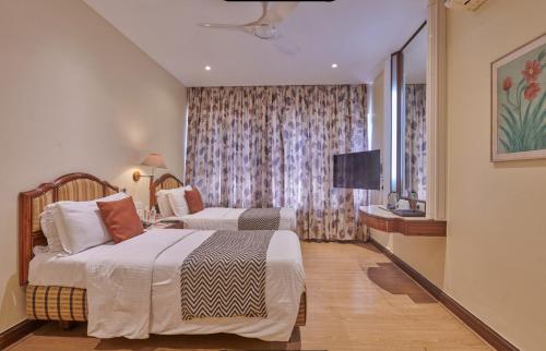孟买Regent Hotel Andheri的酒店客房设有两张床和电视。