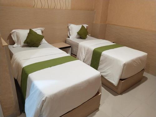 帕卢Hotel Kembang Joyo的小客房内的两张床,配有白色和绿色床单
