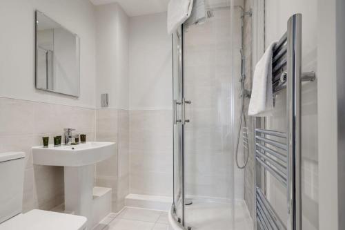利兹Beautiful 2 Bed Apartment in a Converted Mill的带淋浴和盥洗盆的白色浴室