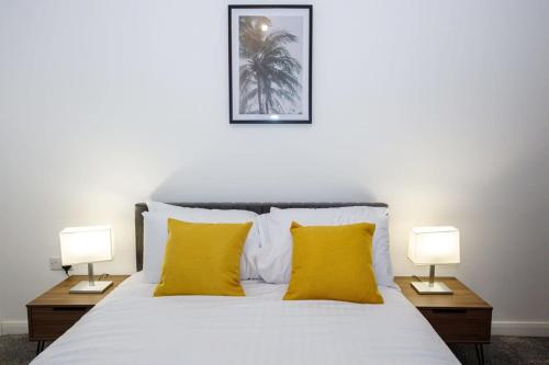 博尔顿Contemporary 1 Bed Apartment Central Bolton的一间卧室配有一张带黄色枕头的床和两盏灯。