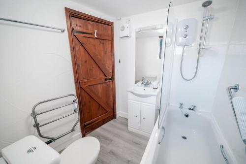 布德Lovely 2 Bedroom Coastal Cottage near Bude的浴室设有木门、卫生间和水槽。