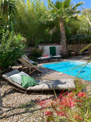 滨海萨纳里Maison d hôtes LA VILLA MADELEINE的度假村旁的游泳池及其躺椅