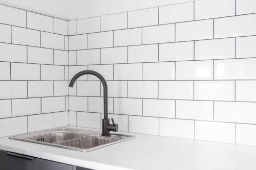 布雷得佛Modern 2 Bedroom Apartment in Central Bradford的厨房设有水槽和白色瓷砖墙。