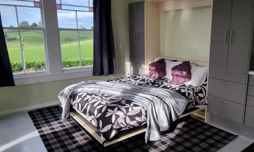 汉密尔顿Sunshine Studio的一间卧室配有一张带紫色枕头的床