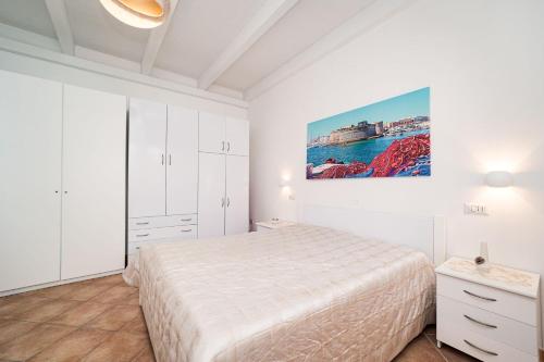 托雷苏达Villa Geraldina con piscina的白色卧室配有一张床,墙上挂着一幅画