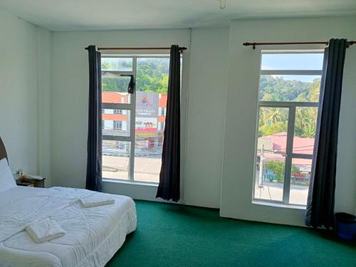 Kampong Tebing RabakHASD GUESTHOUSE的一间卧室设有一张床和两个大窗户