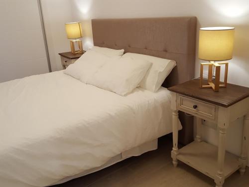 卡拉费尔Mandala apARTments的一张带白色床单的床和一个带两盏灯的床头柜