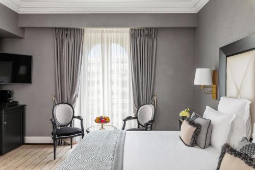 戛纳雄伟戛纳巴里耶尔酒店的一间卧室配有一张床、两把椅子和一个窗户