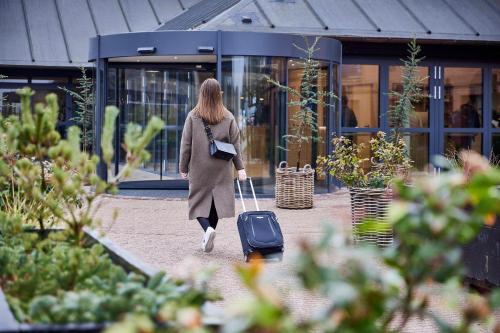 欧登塞欧登塞酒店的一位在大楼前带着手提箱走路的女人
