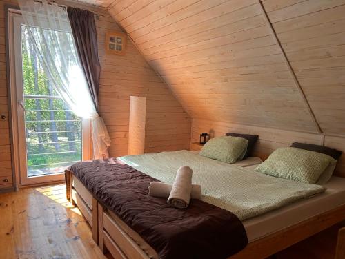 加茨比亚格拉Resort EDEN - domki, pokoje, apartamenty的木制客房的一张床铺,设有大窗户