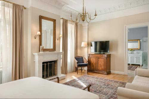 雅典贵族套房公寓式酒店的客厅设有壁炉和电视。