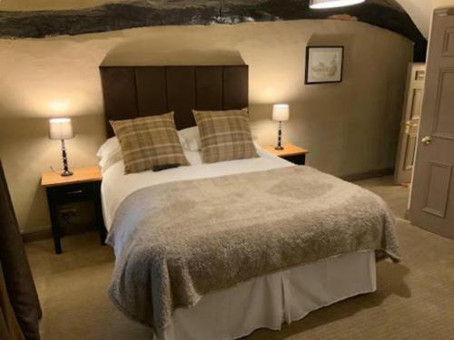 韦瑟比Swan & Talbot Inn的一间卧室配有一张大床和两张台灯。