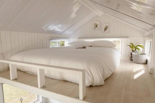 PalmwoodsKookaburra Cabin的一间位于阁楼的白色卧室,配有一张大床