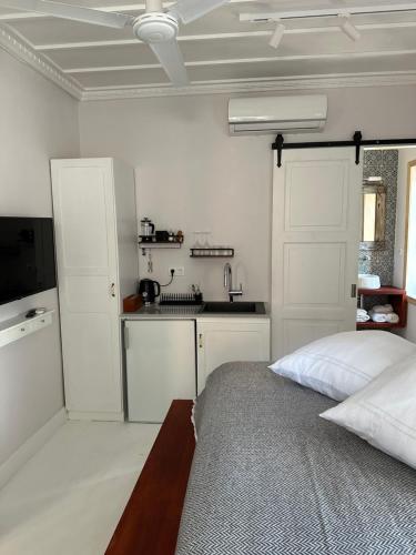 迈伊斯蒂Castellorizon Pensione的一间白色卧室,配有床和厨房