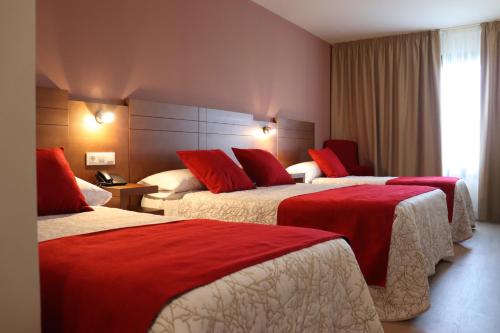 阿尔苏阿HOTEL ARZÚA的酒店客房 - 带两张带红色枕头的床