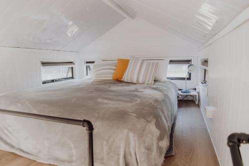 Ringtail CreekNoosa Tiny Home的一间白色客房内配有一张大床的卧室