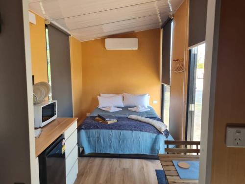 WillungaAlma's Tiny House的一间小卧室,配有一张床和电视