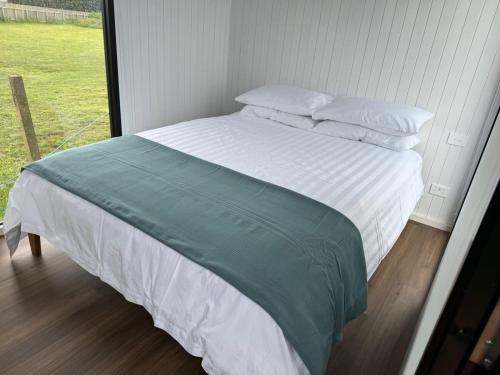 Otaki BeachRangiuru Stream Tiny home的一张带白色床单和枕头的床以及窗户