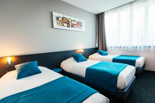 斯特拉斯堡Hôtel Restaurant Athena Spa的酒店客房设有两张床和窗户。